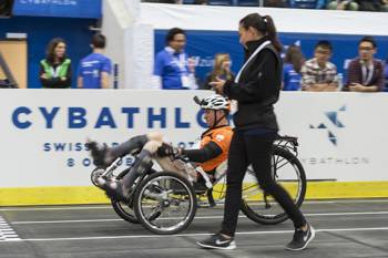 A man in a wheelchair finishes the cybathlon race as a woman next to him follows him